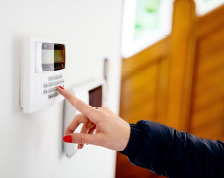 A woman enters a security code into her home smart alarm system.